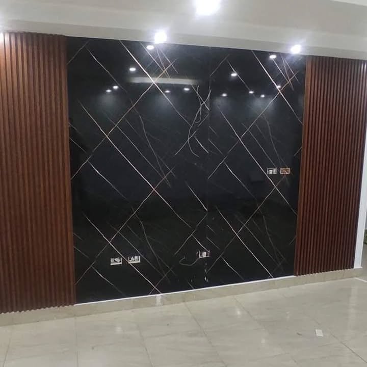 فني ديكورات بالشرقية يقوم بتركيب شرائح بديل الخشب المضلع وبديل الرخام لشاشة تلفزيون بصالة فيلا حديثة